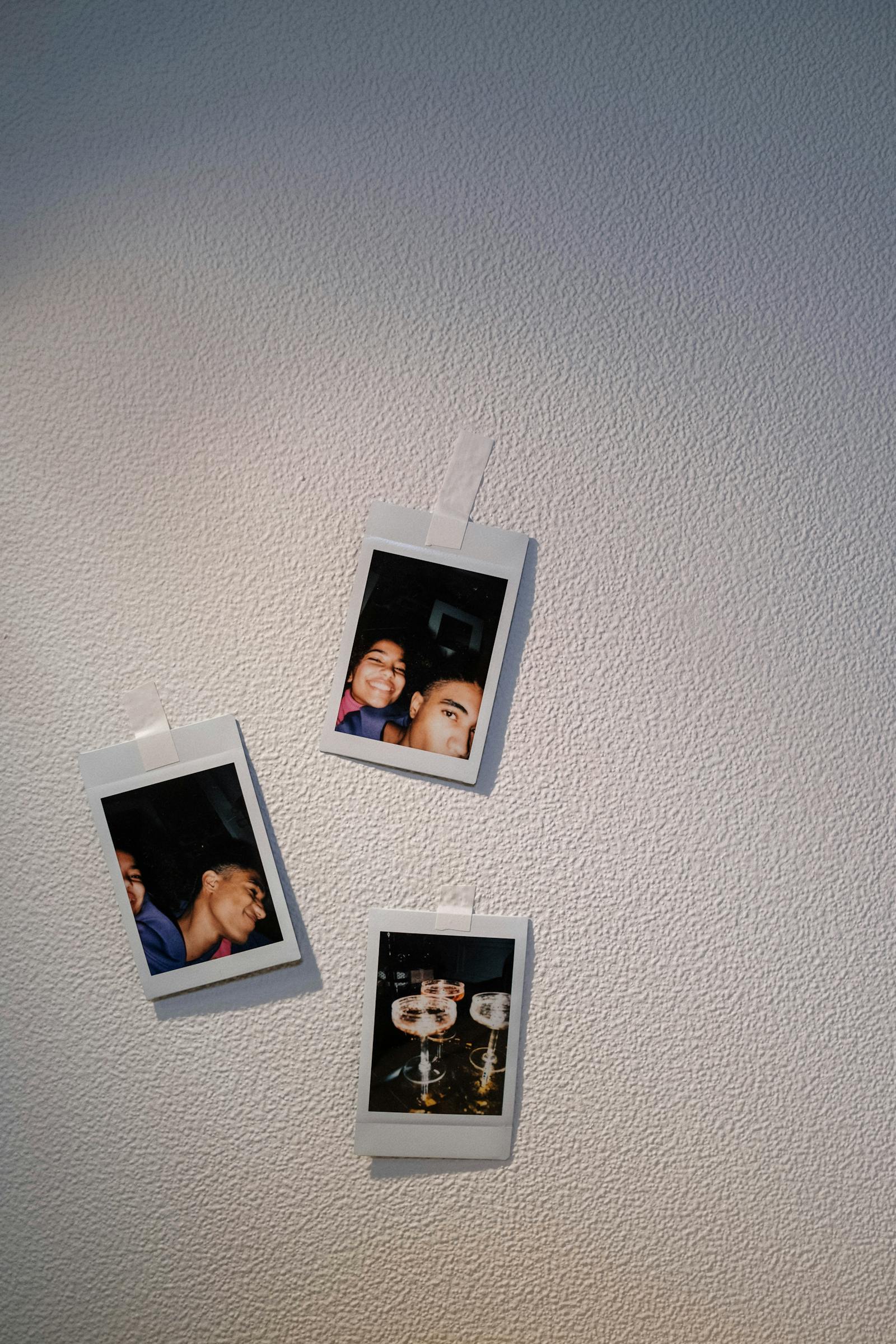 Polaroids penduradas em parede de concreto formando mural pessoal